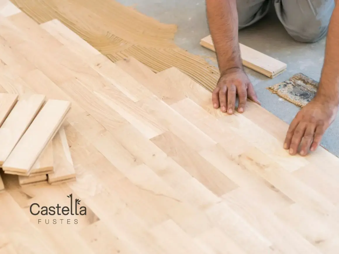 Man installing a light-colored suelo laminado, placing planks on adhesive.