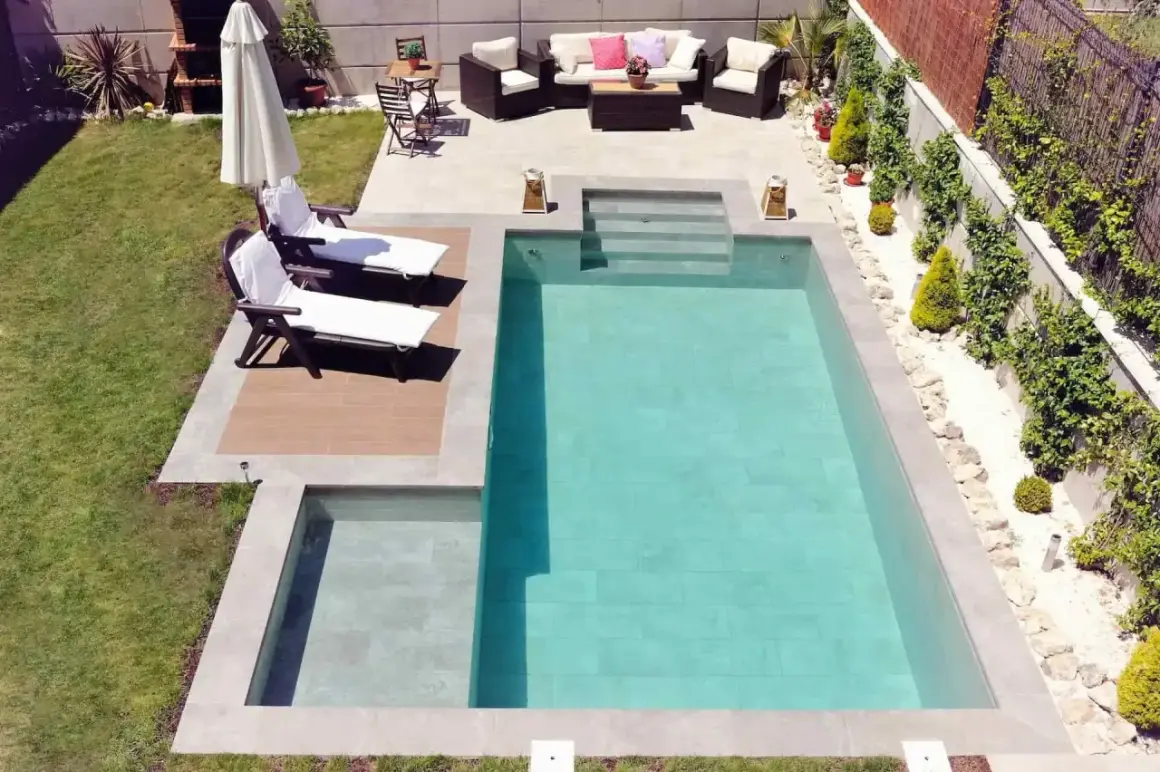 Un jardín listo para construir piscina, con tumbonas, zona de estar y barbacoa.