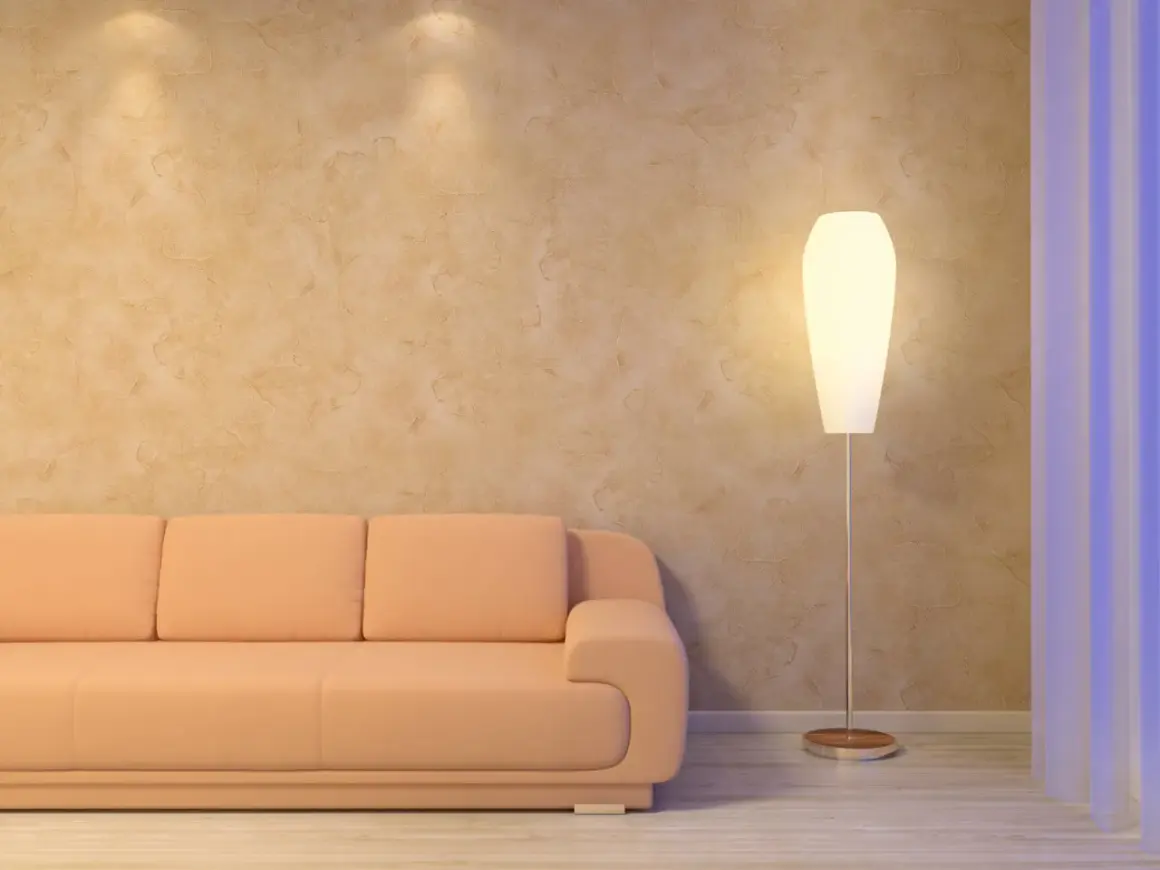 Sofá naranja junto a una lámpara de pie, con una pared texturizada que parece estucar una pared con un acabado rústico.
