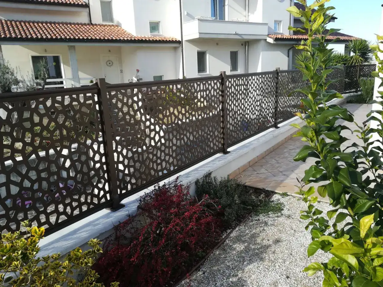 Modern metal fence with geometric cutouts, offering privacy and style. Perfect for ideas ocultaci&oacute;n jardin that blend aesthetics and function.