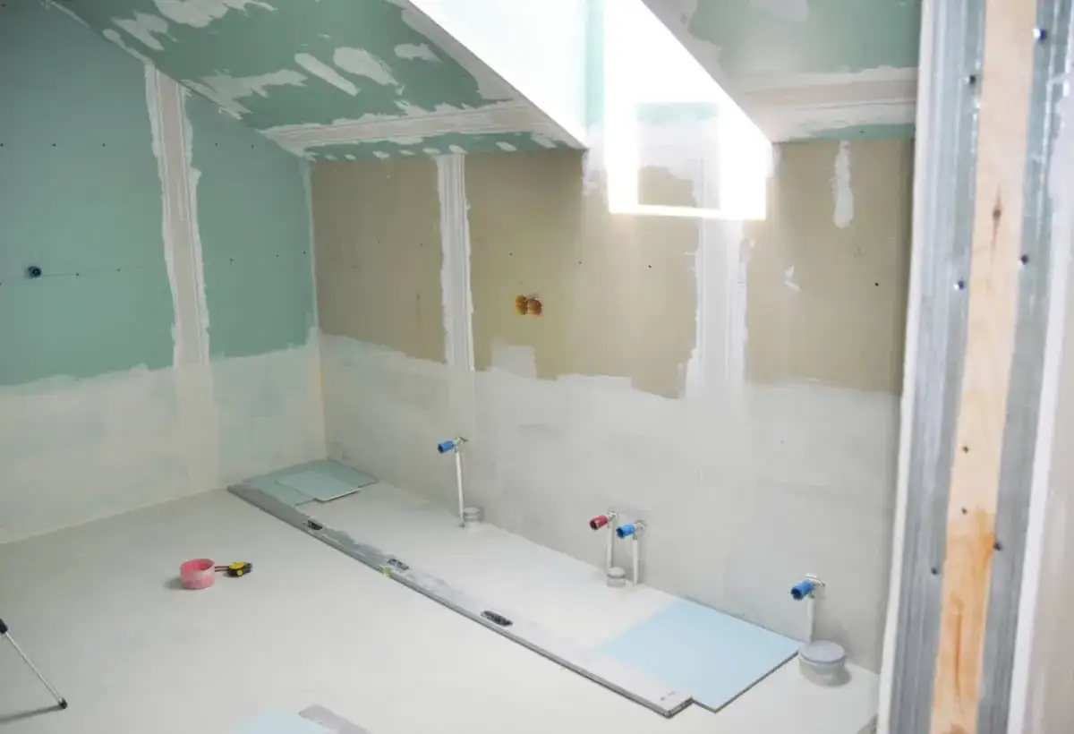 Instalaci&oacute;n de pladur para ba&ntilde;os en obra. Se aprecian tuber&iacute;as de agua y nivel de burbuja.