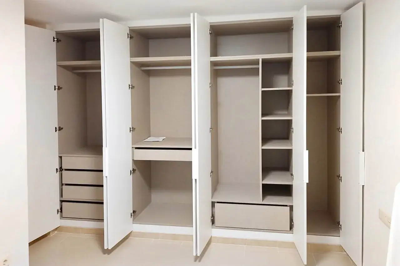 Armario empotrado con puertas abiertas, mostrando estantes, cajones y barras para colgar. Ideal para forrar armario empotrado y organizar tu ropa.