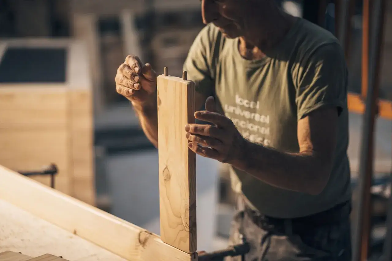 Carpintero ensambla piezas de madera, un ejemplo de c&oacute;mo reparar madera da&ntilde;ada con precisi&oacute;n y cuidado.