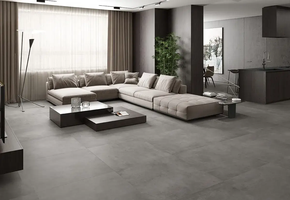 Modern living room with sectional sofa, coffee tables, and a sleek kitchen. The grey tile floor is perfect to change the look of any casa.