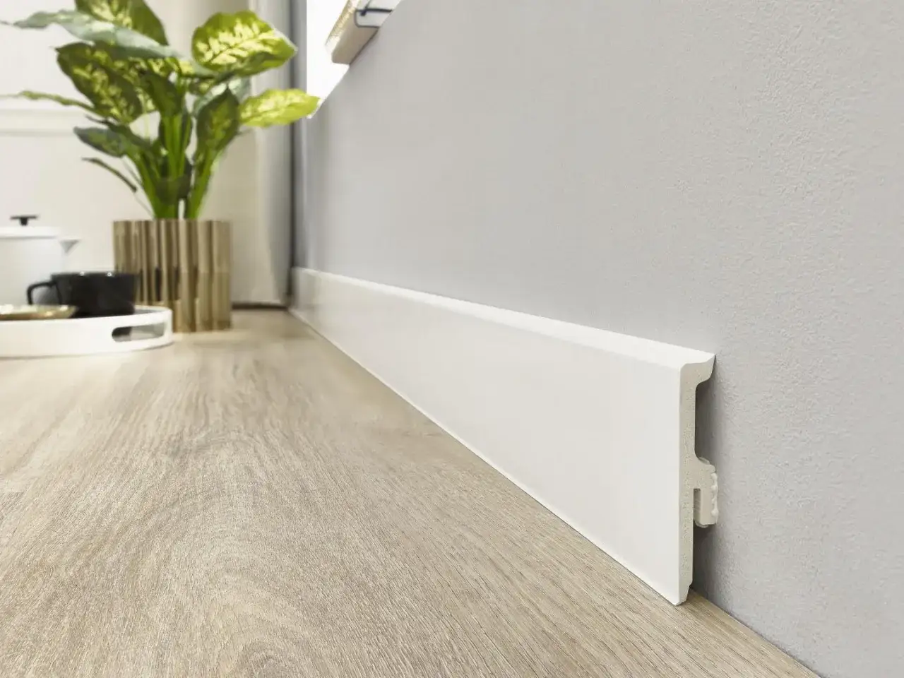 Rodapi&eacute; blanco moderno sobre suelo de madera clara. Un toque de elegancia minimalista que realza la calidez del hogar.