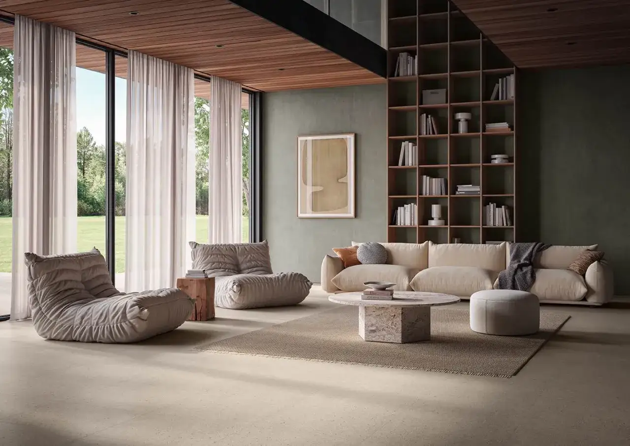 Salón moderno con sofás cómodos, estantería llena de libros y un elegante revestimiento del suelo que aporta calidez.