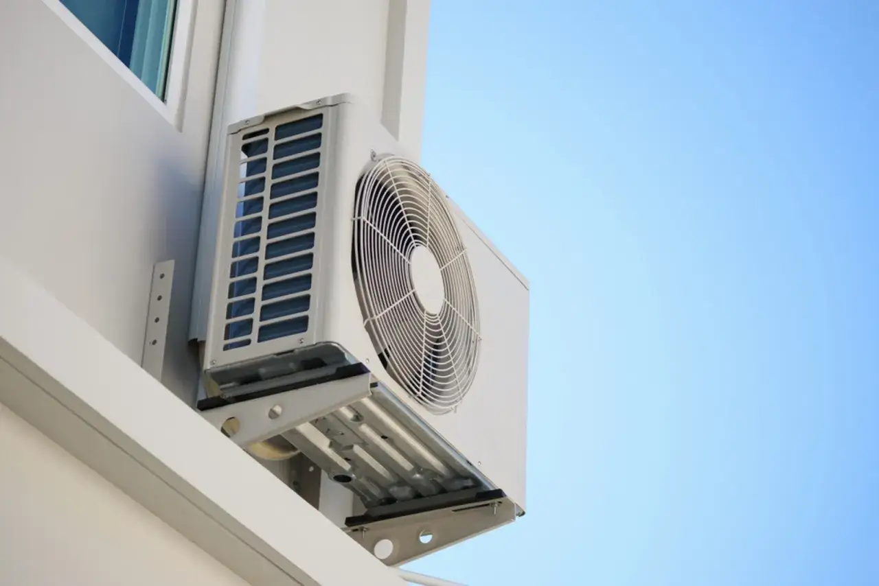 Unidad exterior de aire acondicionado montada en la pared de una terraza cerrada, lista para refrescar el ambiente.