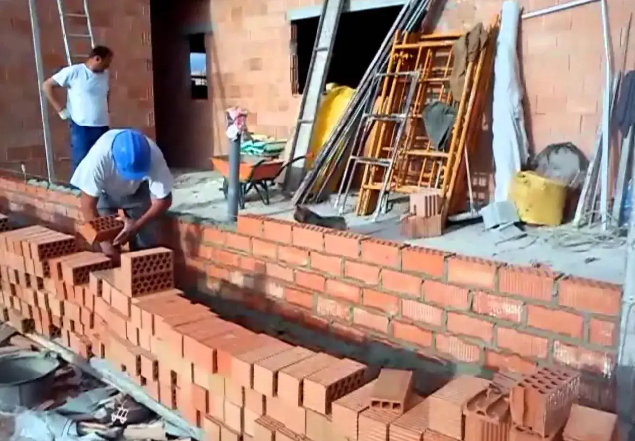 Obrero coloca ladrillos para construir diferentes tipos de muros de ladrillo. Andamios y materiales de construcción en el sitio.