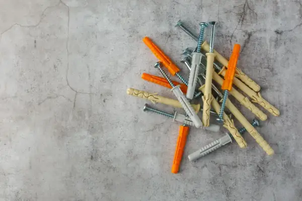 Montón de tacos de pared de varios colores (naranja, beige, gris) con tornillos. Listos para fijar cualquier cosa a la pared.