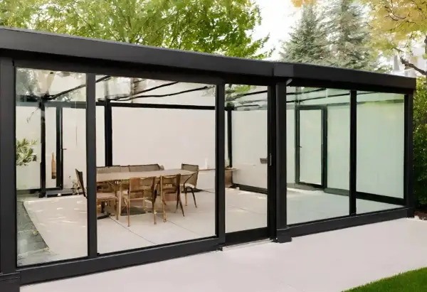 Modernos tipos de cerramientos de cristal con mesa y sillas en el interior, creando un espacio elegante y luminoso.