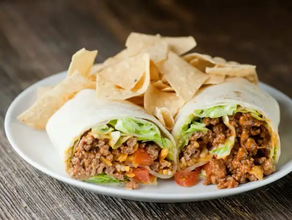 Un taco quimico como funciona: carne molida, lechuga, tomate y queso envueltos en tortilla, servido con totopos.