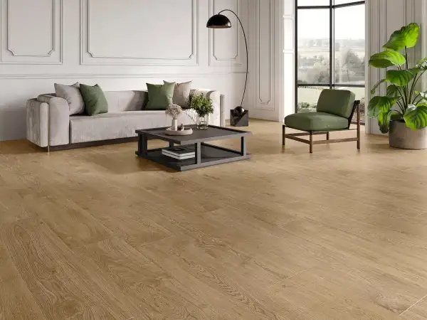 Elegante salón con sofá gris, sillón verde y un moderno revestimiento del suelo de madera clara que aporta calidez.