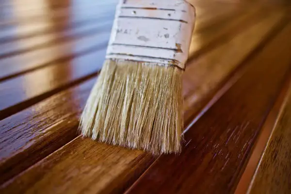 Brocha aplica barniz a listones de madera, dándoles un acabado brillante. El proceso de blanquear madera puede ser el primer paso para un nuevo look.
