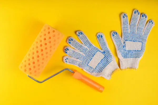 Rodillo de esponja naranja y guantes de trabajo azules, listos para diferentes tipos de rodillos para pintar.
